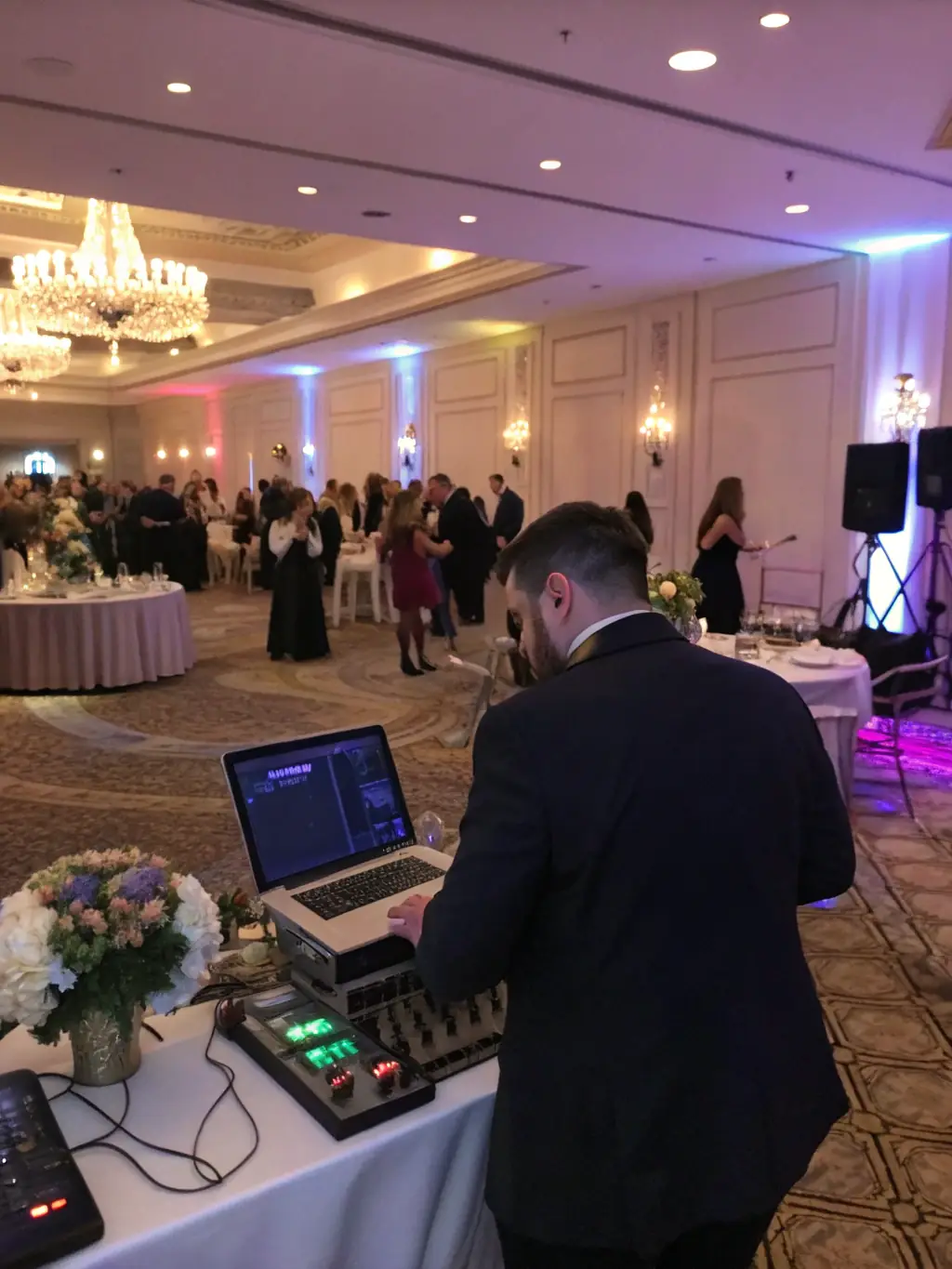A sophisticated corporate event with a DJ providing background music during a networking session. Attendees are engaged in conversation and enjoying the ambiance.